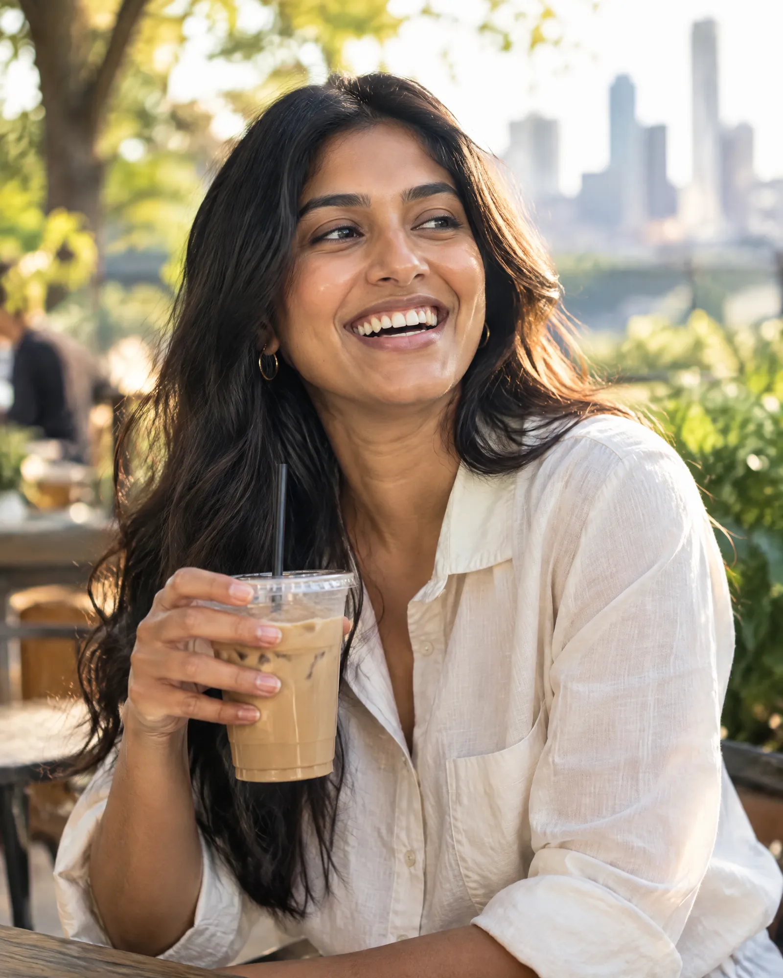 A young woman laughing on a sunny café patio